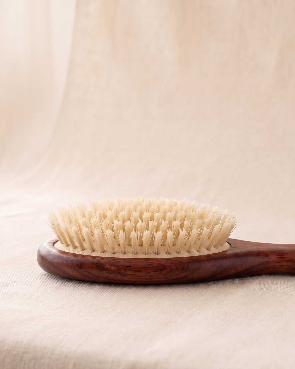 Side view of the brush head showing rows of boar bristle tufts set apart on a cushion