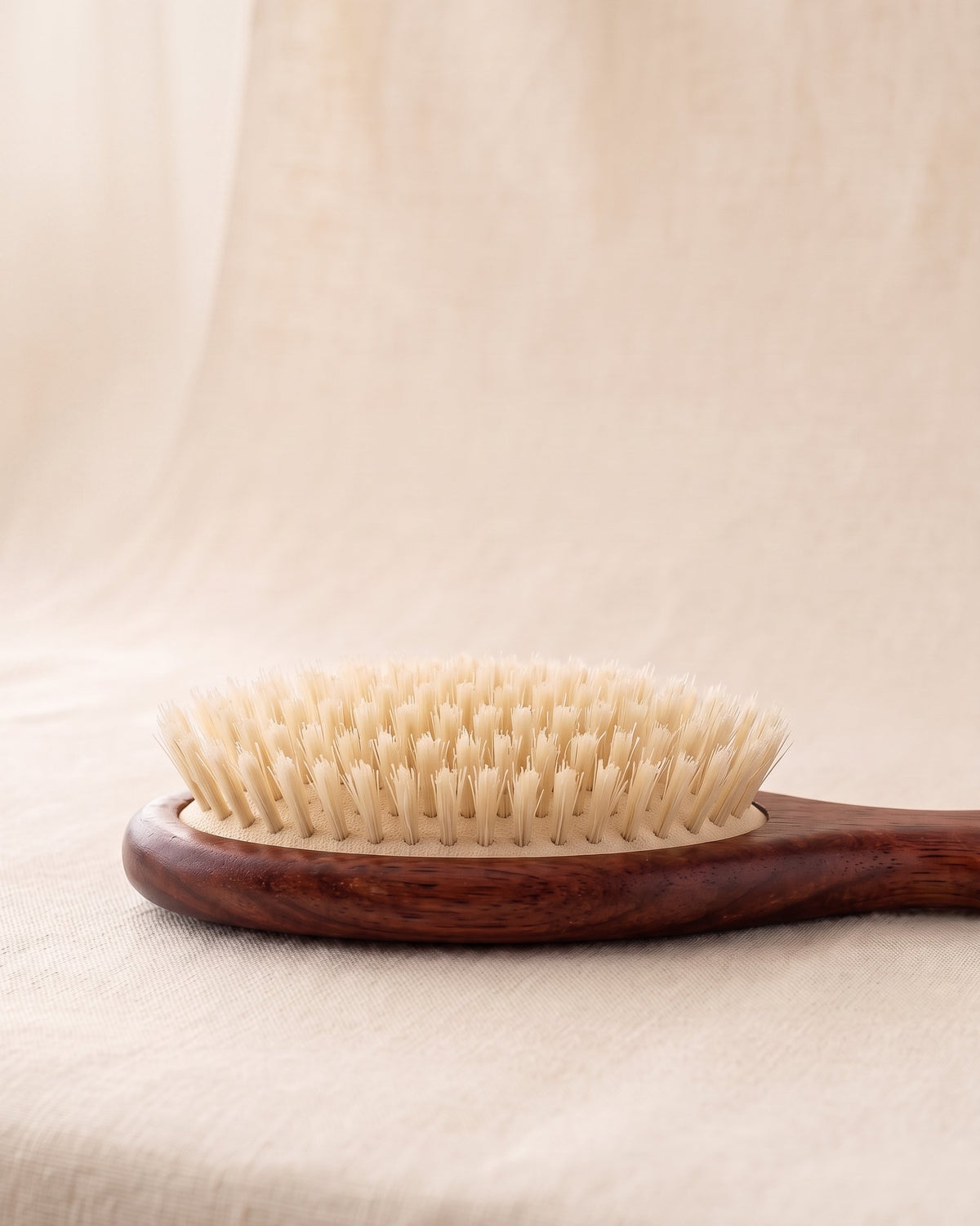 Side view of the brush head showing rows of boar bristle tufts set apart on a cushion